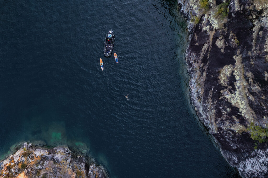 Zodiac drone shot of paddlers and guests swimming in remote location